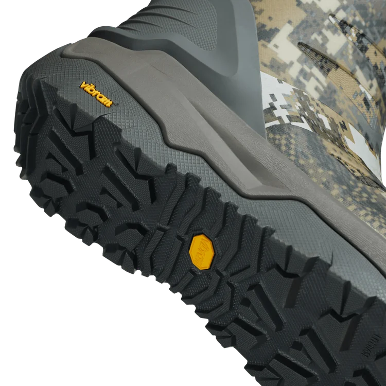 Close-up of a boot sole with tread pattern and Vibram branding, on a camouflage background.