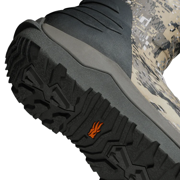 Close-up of a boot sole with tread pattern and brand logo, on a camouflage background.