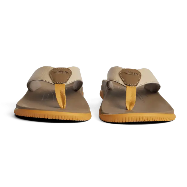 Pair of beige sandals with yellow soles on a white background