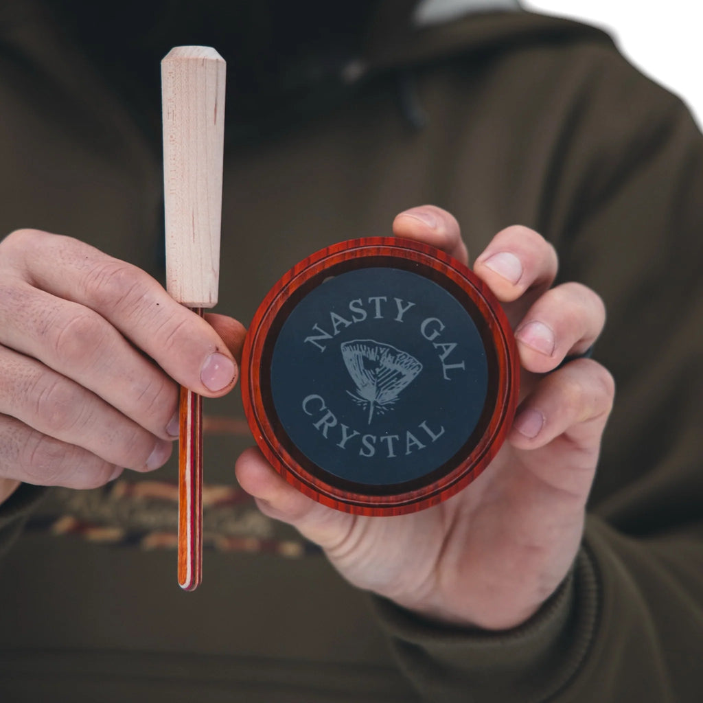 Person holding a wooden tool and a container labeled 'Nasty Gal Crystal'.