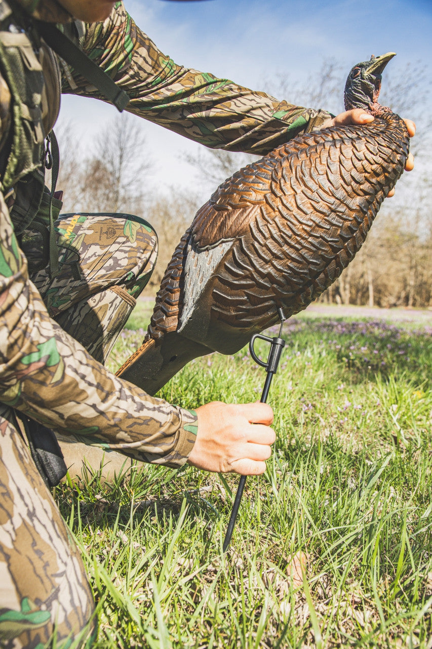 Person in camouflage holding a turkey in an outdoor setting