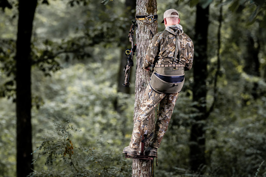 Person in camouflage gear on a tree stand in a forest