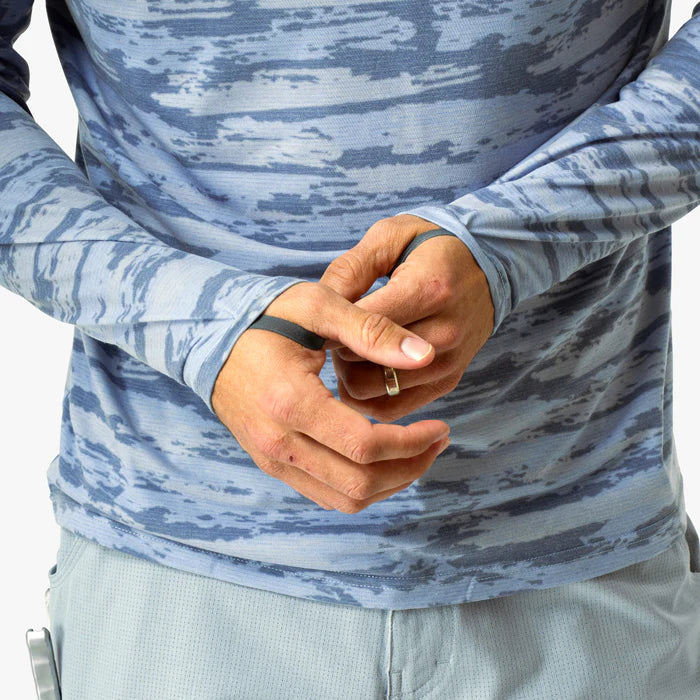 Person wearing a blue camouflage long-sleeve shirt with hands clasped together.