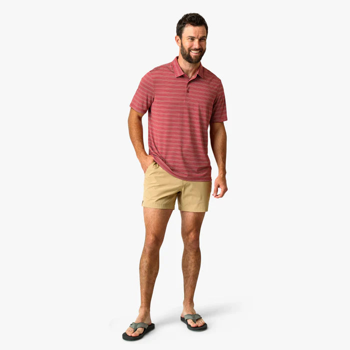 Man wearing a red striped polo shirt and beige shorts on a white background