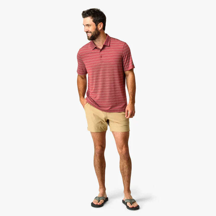 Man wearing a red striped polo shirt and beige shorts on a white background