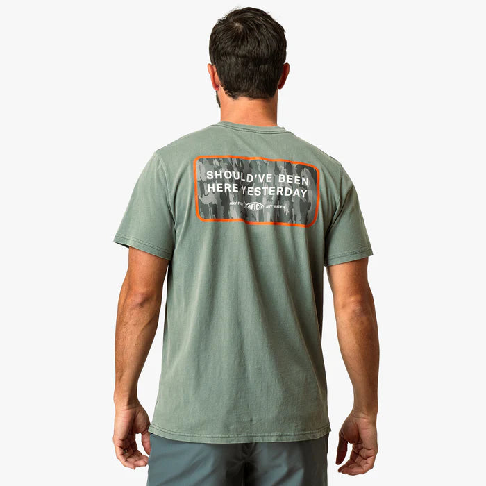 man wearing green shirt with logo on a white background