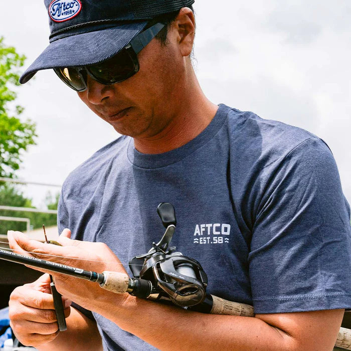 Person wearing a blue shirt and hat holding a fishing rod