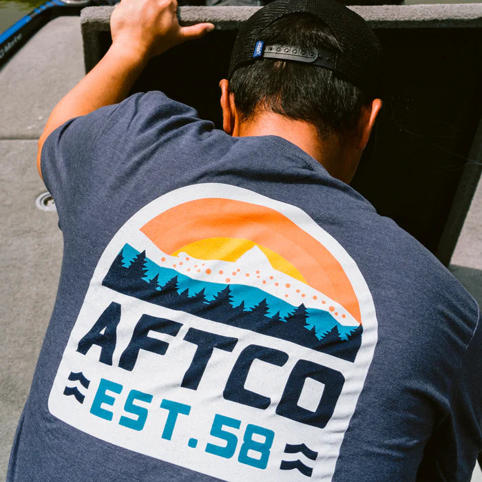 Person wearing a blue t-shirt with AFTCO logo and text, standing on a boat deck.