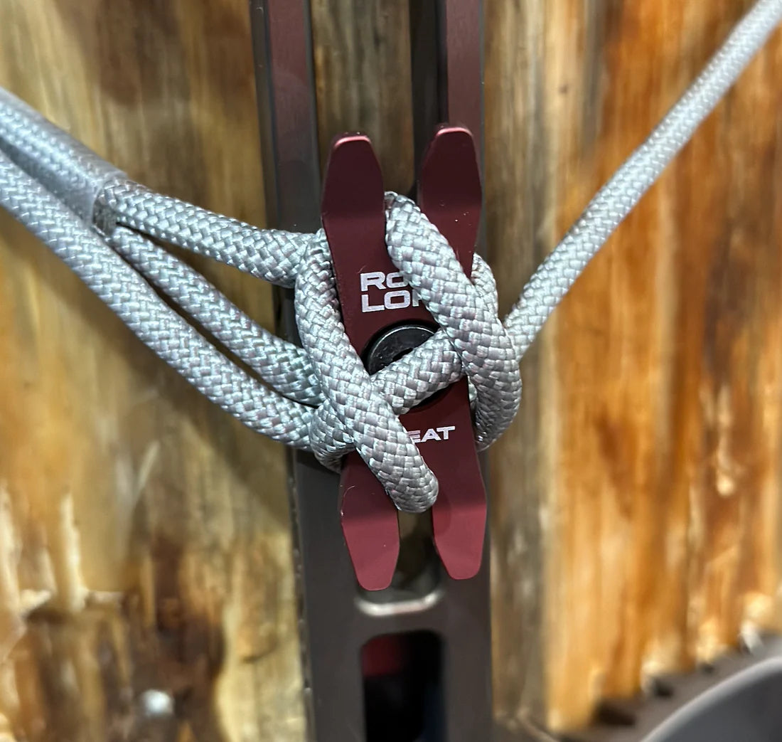 Close-up of a rope tied to a metal clip with a wooden background