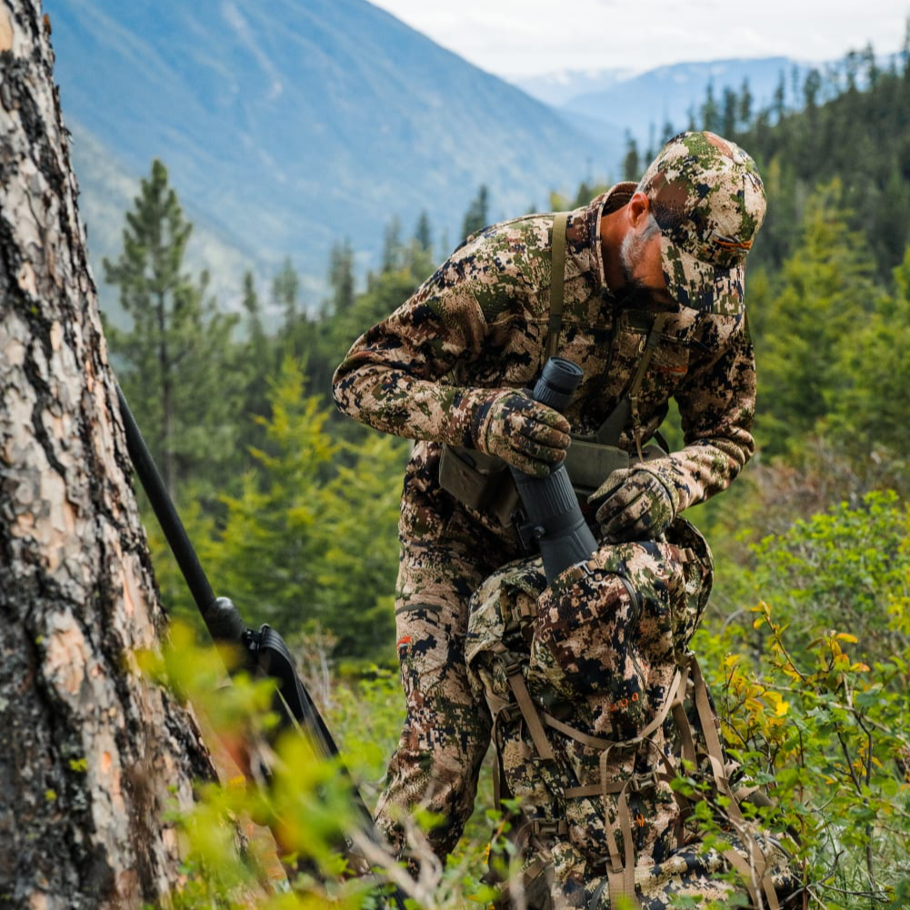 Hunter in camouflage gear in a forested mountain area