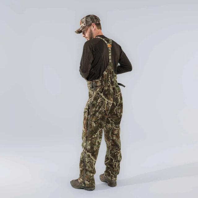 Man wearing camouflage overalls and a cap on a white background