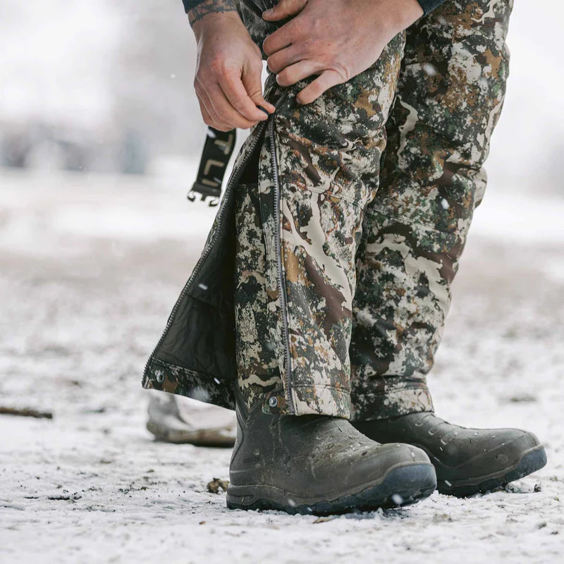 Person wearing camouflage pants and boots in a snowy environment