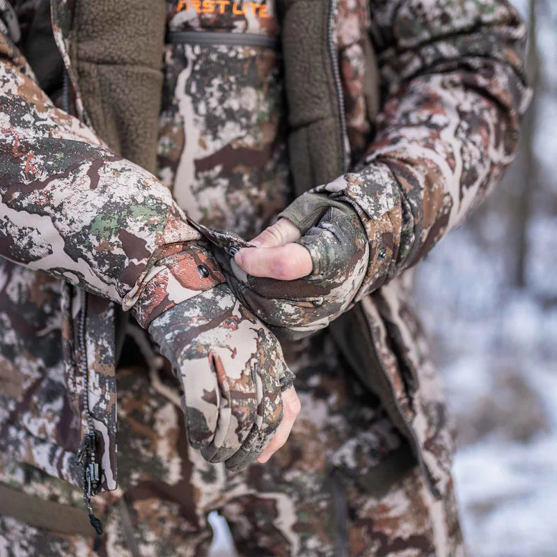 Person wearing camouflage hunting gear with a focus on hands holding a bow.