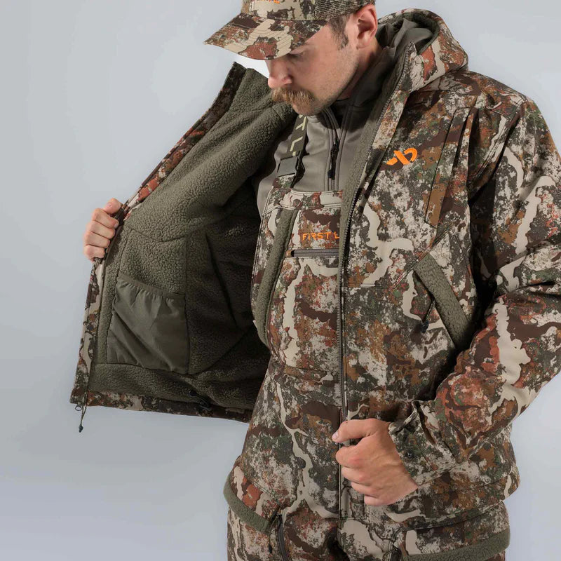 Man wearing full camouflage hunting gear with a visible brand logo on a light gray background
